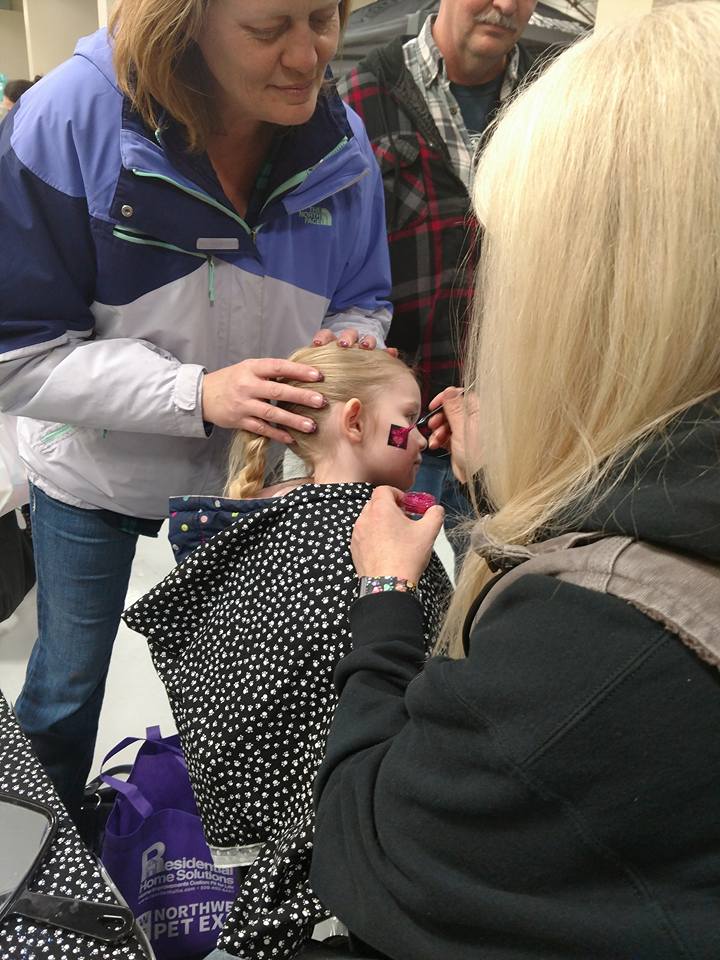  Young girl getting a glitter tattoo on her cheek 